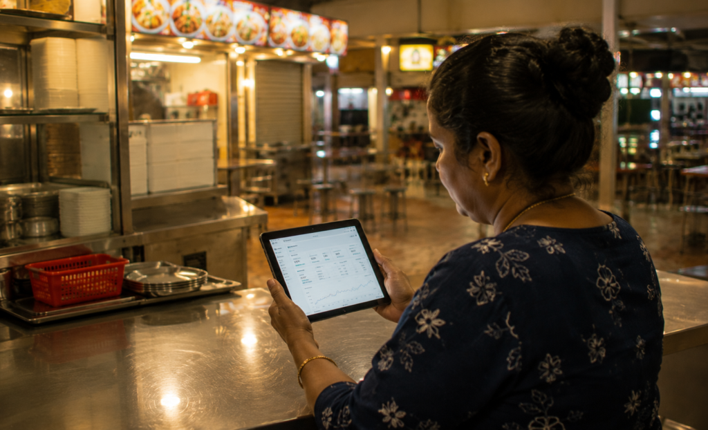 Hawker stall owner reviewing daily sales recap on tablet at closing time - Labamu Singapore